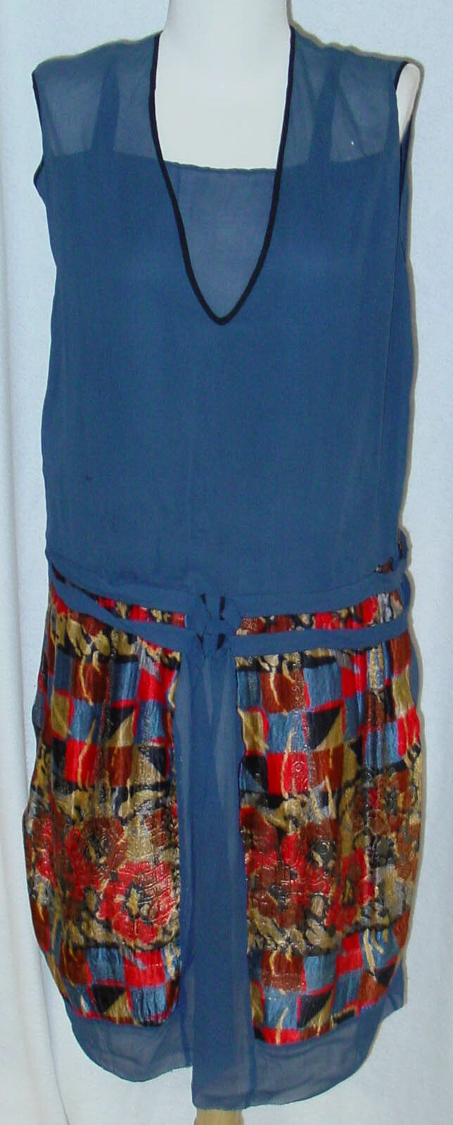 This evening dress from about 1926, an example of Jazz Age fashion, is made of dark blue pure silk chiffon and features a skirt with a Persian pattern over a Cubist background. It is one of the earliest items in the Mackenzie collection. Canterbury Museum 1984.70.454