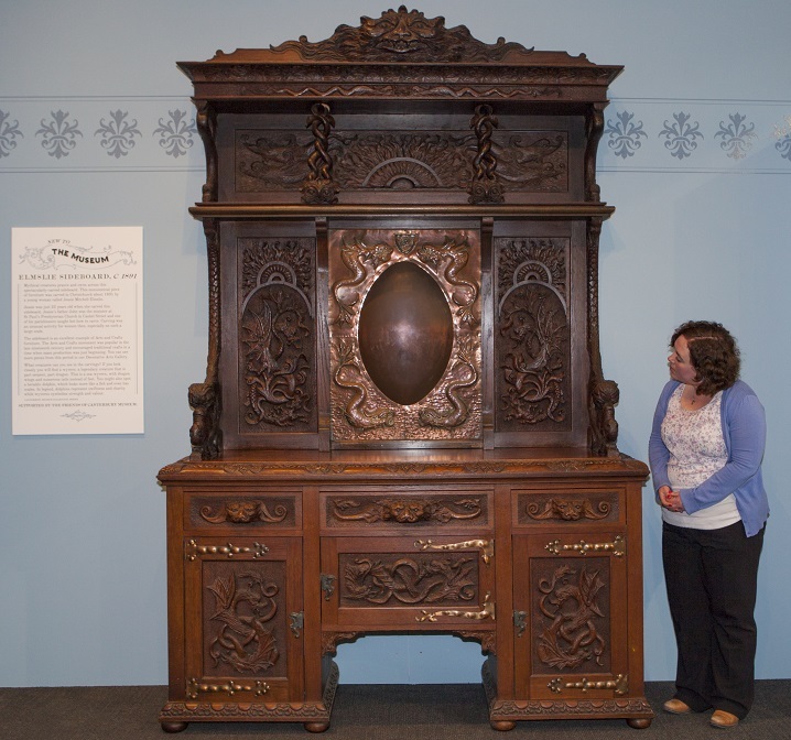 Canterbury Museum Curator, Marguerite Hill with the Elmslie Sideboard in the Museum foyer.