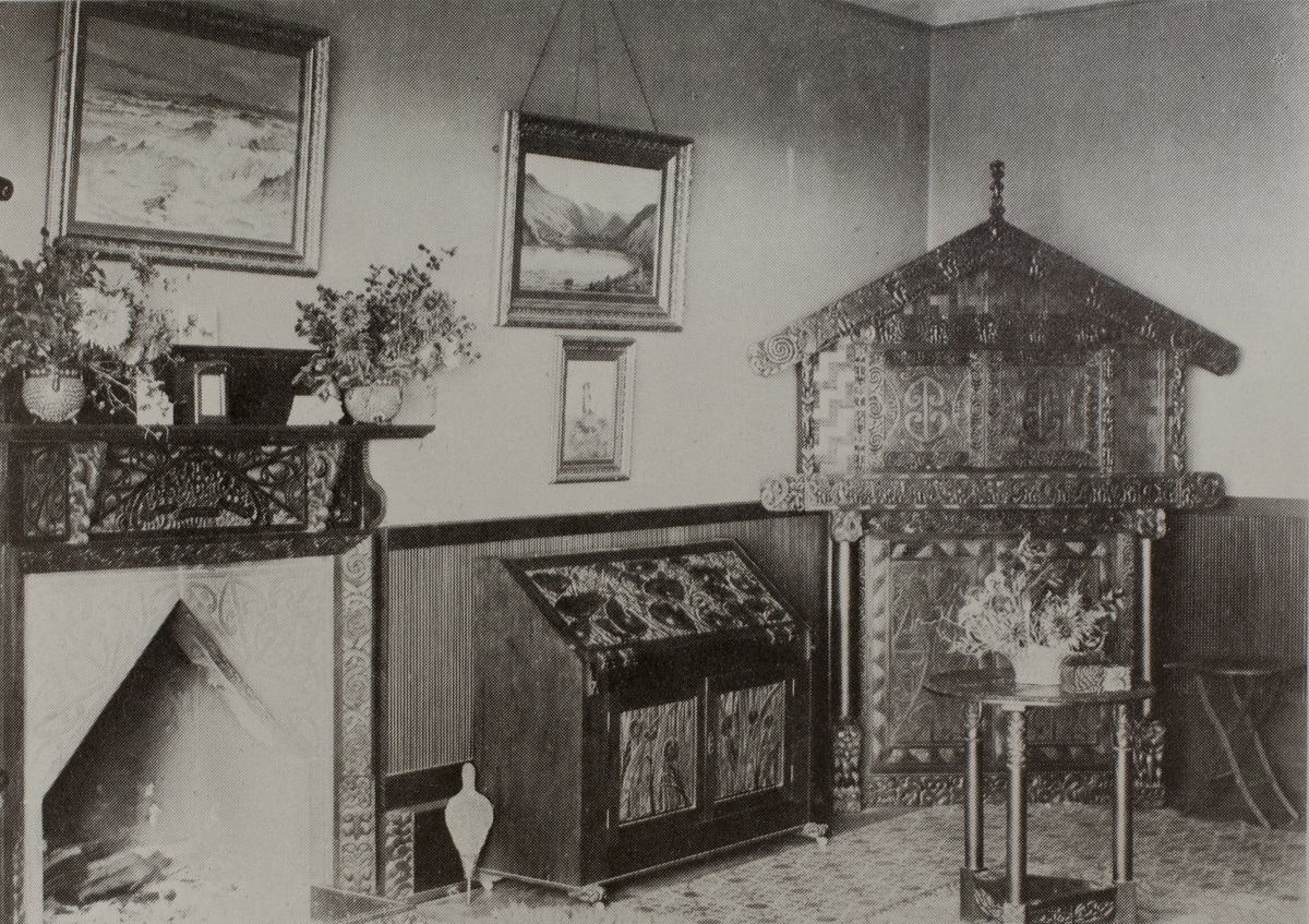 The drawing room at Rehutai, c1900. The fireplace was decorated with carved Māori patterns and figures, and the room contained pieces of furniture that Menzies had carved. Note the large cupboard that is based on a pātaka storehouse and next to it a drop-front desk with Mount Cook lilies. Photographer unknown, reproduced from Ian Menzies, The Story of Menzies Bay, Pegasus Press, 1970. All Rights Reserved